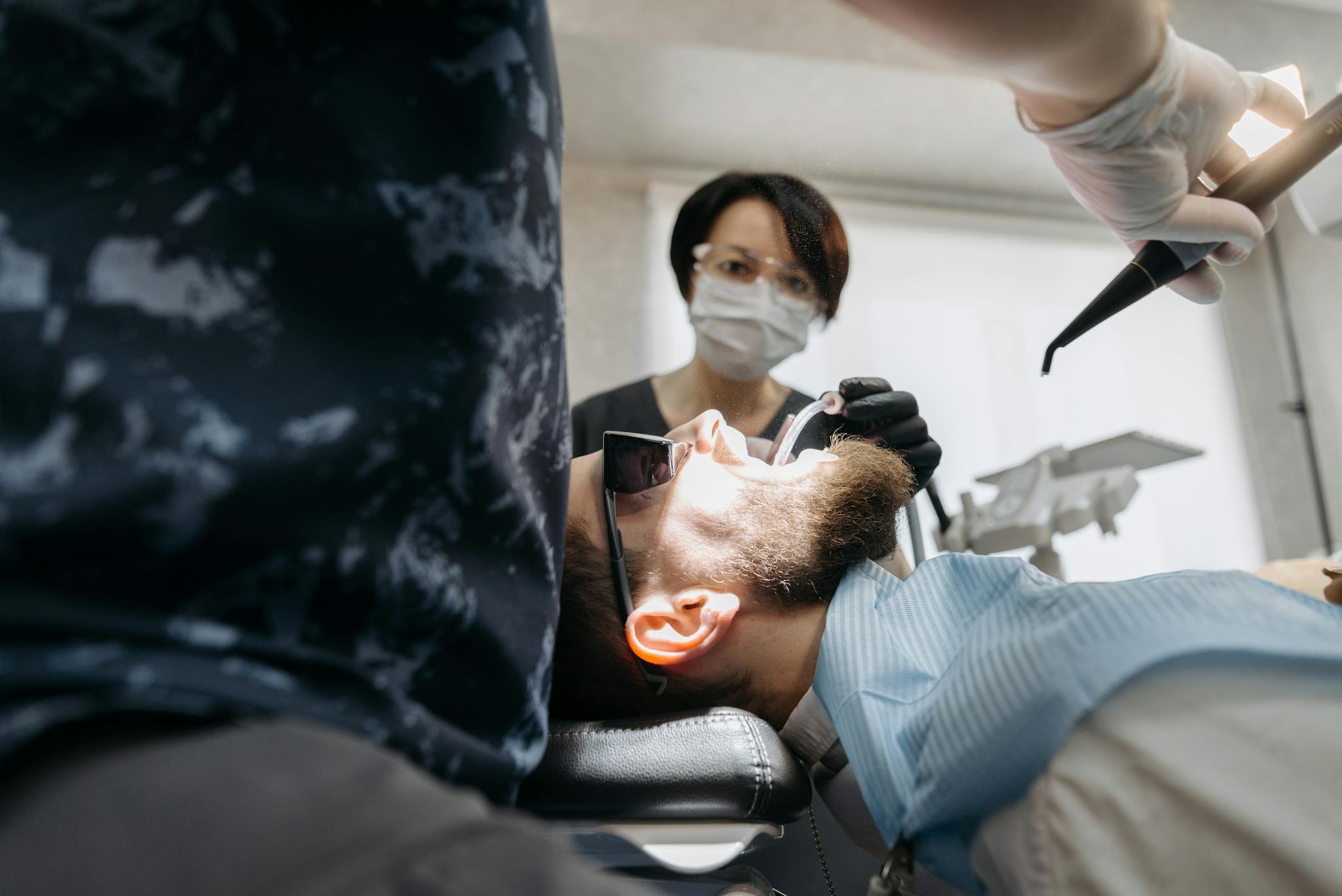 Dentist examining patient's teeth using dental tools at a clinic.